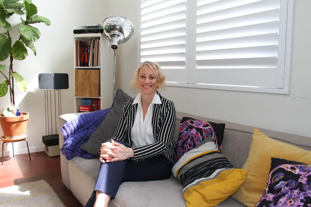 Kiah Bouchet sitting on a grey couch in a light-filled living room