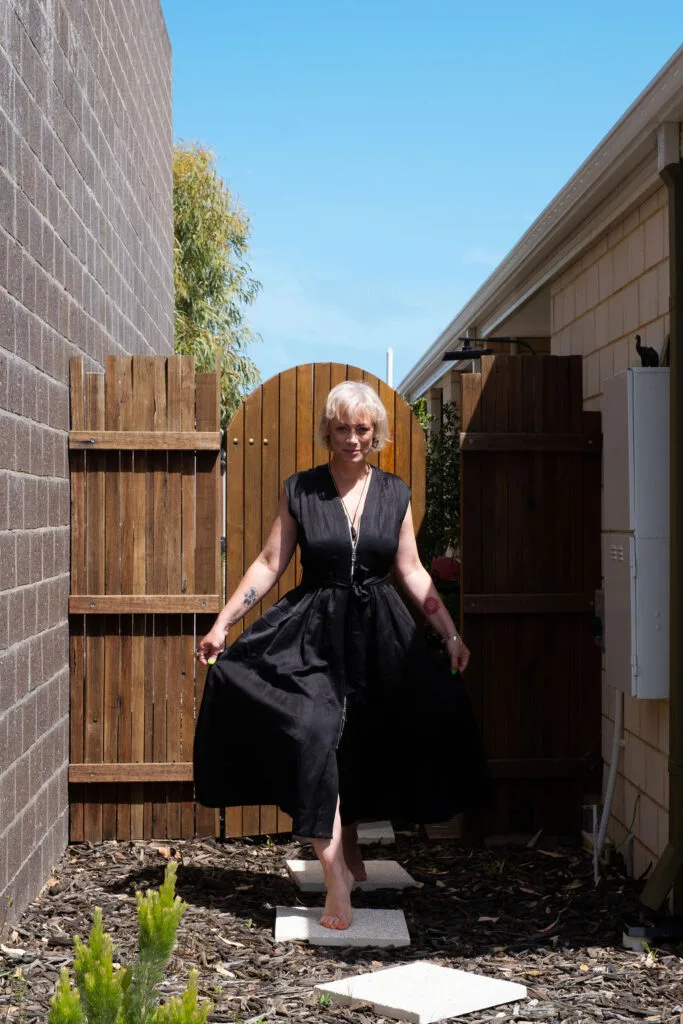 Kiah Bouchet walking through a timber side gate towards a client visit in Perth